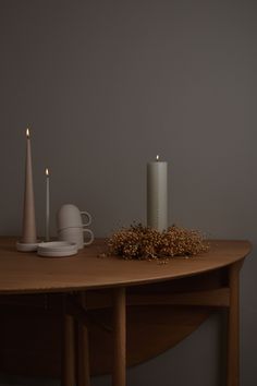 two candles are sitting on a table next to a cup and saucer