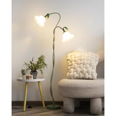 a lamp that is sitting next to a table with a pillow on it and a potted plant