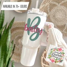 a white tumbler with the name bailey on it next to a potted plant