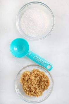 two bowls filled with sugar and an empty bowl full of sugar next to a blue measuring spoon