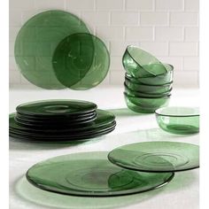 green glass plates stacked on top of each other in front of a white brick wall