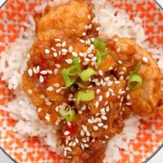 an orange and white plate topped with rice, meat and veggie covered in sesame seeds