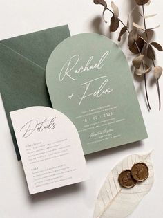 the wedding stationery is laid out on top of the table with leaves and coins