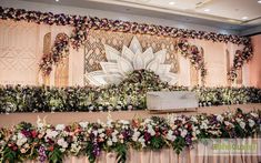 an arrangement of flowers and greenery decorates the backdrop for a wedding ceremony in front of a stage