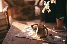 a table topped with a vase filled with white flowers next to a cup and saucer