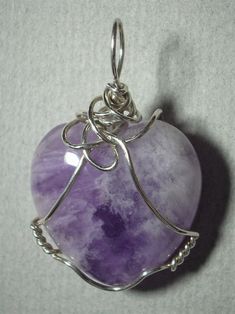 Amethyst Heart Pendant Wire Wrapped in .925 Sterling Silver Round Wire An ennobling stone heart of varied white, clear and light transparent purple coloration with multiple internal reflecting and refracting crystal planes; it especially compliments pink, purple, red, burgundy, and blue colors of clothing, wears well with light to dark color combinations, appearing darker purple against darker backgrounds; The heart shape may appeal to a purist view, but a visible crystal plane pattern, and vari Purple Double Heart Charm Jewelry, Purple Double Heart Jewelry With Heart Charm, Lavender Stone Jewelry Gift, Silver Spiritual Heart Cut Jewelry, Heart Shaped Amethyst Jewelry For Wedding, Heart-shaped Amethyst Wedding Jewelry, Purple Sterling Silver Heart Jewelry, Purple Heart Sterling Silver Jewelry, Purple Heart Cut Sterling Silver Jewelry