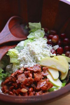 a wooden bowl filled with salad and fruit