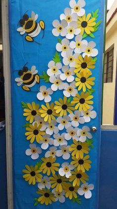 a door decorated with paper flowers and bees on the outside, in front of a blue wall