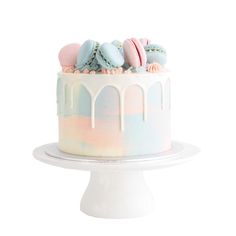 there is a cake with frosting and macaroons on top