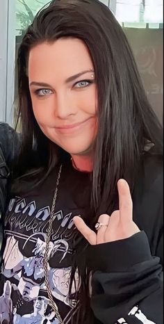 a woman with long black hair giving the peace sign