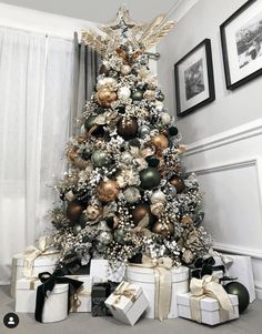 a decorated christmas tree with gold and silver ornaments on it, surrounded by other presents