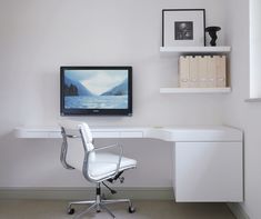 a white chair sitting in front of a desk with a computer monitor on top of it