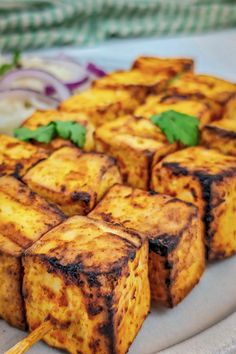 tofu skewers on a plate with onions and cilantro