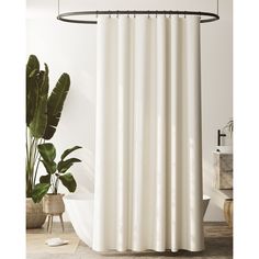 a white shower curtain in a bathroom next to a potted plant