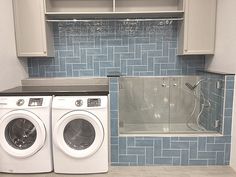 a washer and dryer in a kitchen with blue tiles on the backsplash