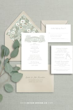 the wedding stationery is displayed with greenery