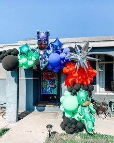 a balloon arch in front of a house decorated with balloons and decorations for a birthday party