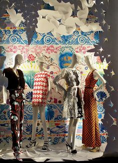 three mannequins dressed in colorful dresses and hats