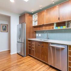 an empty kitchen with wooden cabinets and stainless steel appliances in the center, along with hardwood flooring