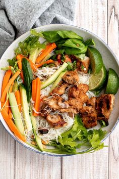 a salad with chicken, carrots, cucumbers and lettuce in a bowl