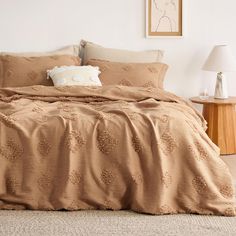 a bedroom with a bed covered in brown comforter and two lamps on the side tables