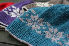 three knitted hats sitting on top of a wooden table