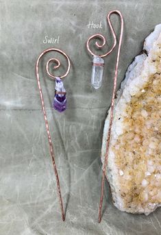 two metal pins sitting next to each other on top of a rock and some crystals