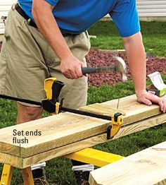 a man using a saw to cut planks on a wooden bench in the yard