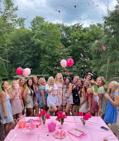 a group of women standing next to each other at a table covered in confetti