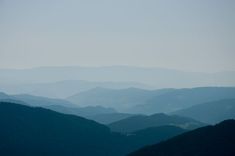 the mountains are covered in fog and haze as seen from an overlook point on a clear day