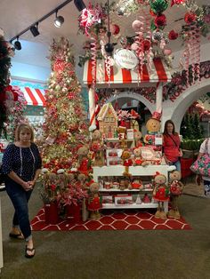 two women are standing in front of a christmas display at the holiday store with many decorations