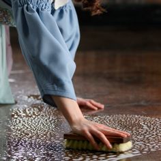 a woman is cleaning the floor with a brush