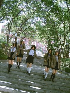 four girls in school uniforms are walking up some steps and one girl is holding her hand out