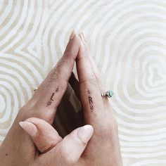 two people holding each other's hands with small tattoos on their thumbnails