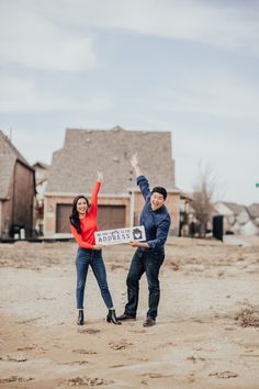 a man and woman standing in front of a house holding a sign with the word california written on it