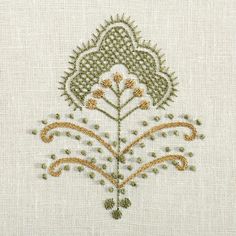 an embroidered design on white linen with gold and green threadwork in the center,