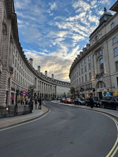 an empty street with cars parked on both sides and people walking along the side walk