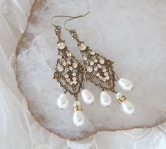 These antique gold bridal earrings are created with highly detailed luxurious antique brass filigree drops in which I placed Swarovski golden shadow crystals, Swarovski ivory pearls and Swarovski rondelles. These dangle dramatically 3-1/2 inches from top of ear wire to bottom of center pearl drop. This is an original design by © Treasures by Agnes PLEASE ALLOW 10 DAYSFOR COMPLETION. All pieces come beautifully gift wrapped. Custom orders welcome. ALL ORDERS ARE SHIPPED VIA USPS FIRST CLASS WITH Antique Finish Bronze Wedding Earrings, Victorian Wedding Earrings With Antique Finish, Antique Bronze Earrings For Wedding, Wedding Pearl Drop Brass Earrings, White Brass Pearl Earrings For Wedding, Antique Finish Drop Earrings For Wedding, Wedding Pearl Drop Earrings In Brass, Ornate Jeweled Earrings For Wedding, Gold Brass Pearl Earrings For Wedding