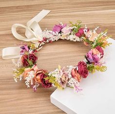 a flower crown on top of a table next to a white box with a ribbon