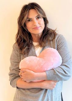 a woman holding a pink heart shaped pillow