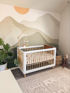 a baby's room with mountains painted on the wall and a crib in the corner