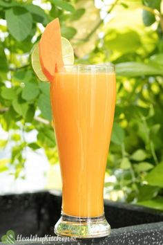 a tall glass filled with orange juice and a slice of lime