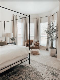 a bedroom with a bed, chair and rug in front of two windows that look out onto the street