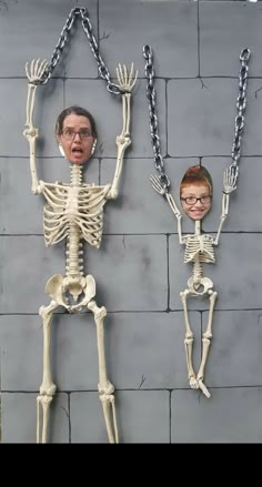 two fake skeletons are hanging on the wall