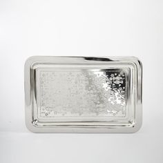 a silver rectangular shaped object with flowers on it's sides and a white background