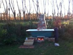 a small child sitting in a bathtub next to a brick fire place and trees