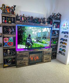 an entertainment center with a large television and many toy action figures on the shelves in front of it