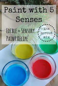 three bowls filled with paint sitting on top of a white paper next to a pine tree