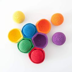 colorful crocheted balls on white surface with one ball in the middle and six smaller ones