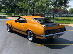 an orange muscle car parked in a parking lot